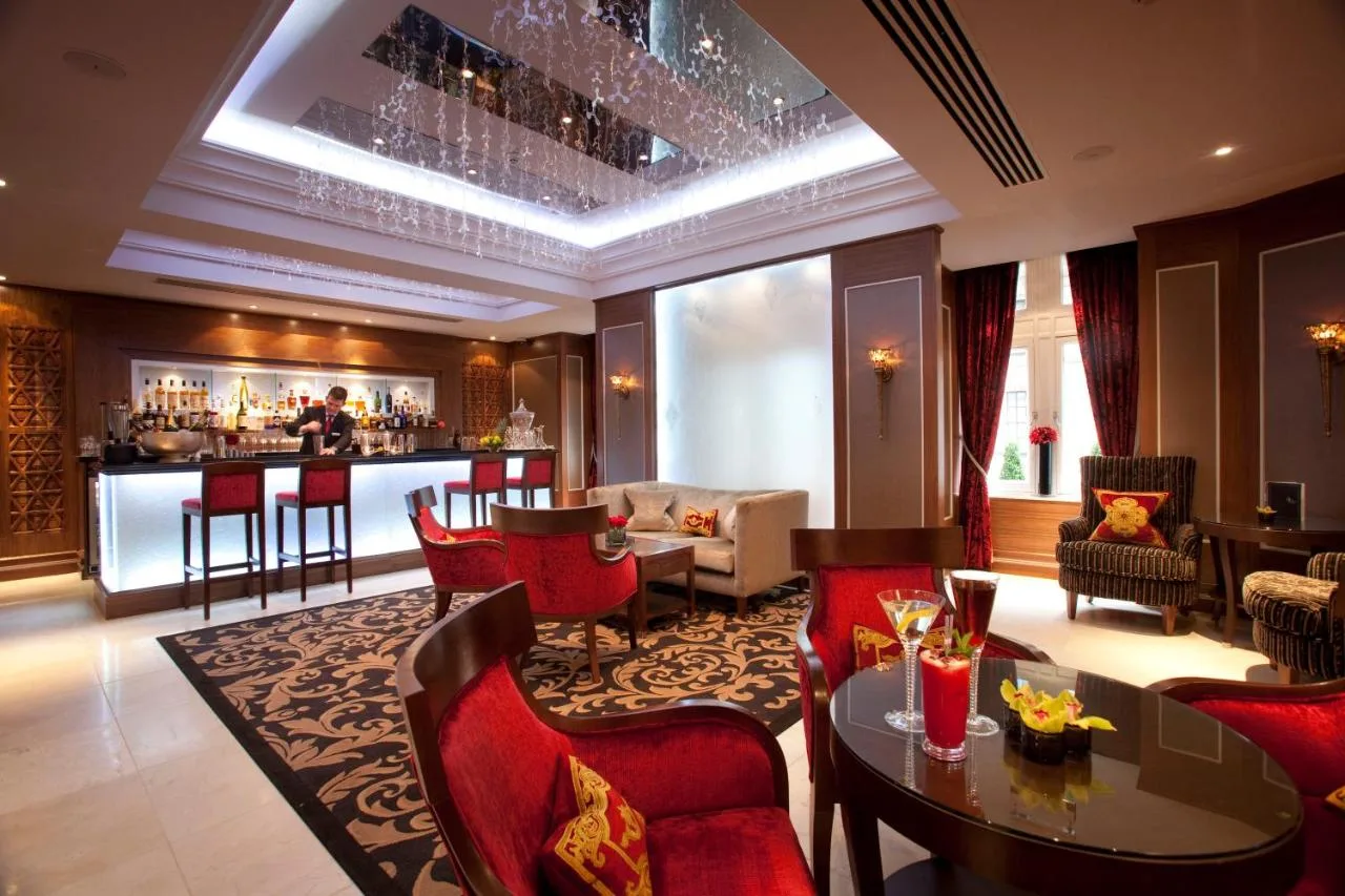 a hotel lobby with a bar and red chairs at The Royal Horseguards Hotel, London in London