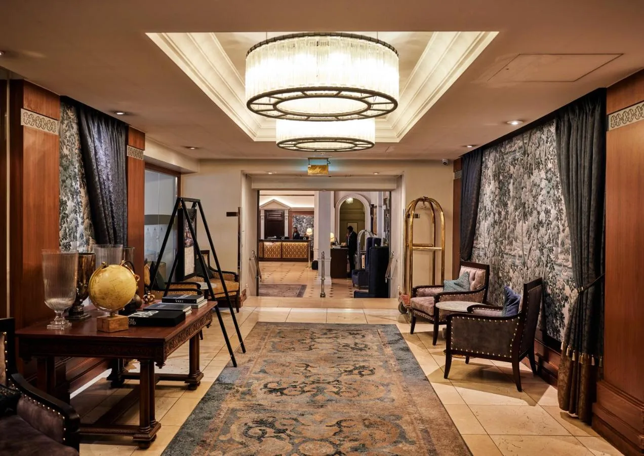 a living room with a table and a chandelier at The Royal Horseguards Hotel, London in London